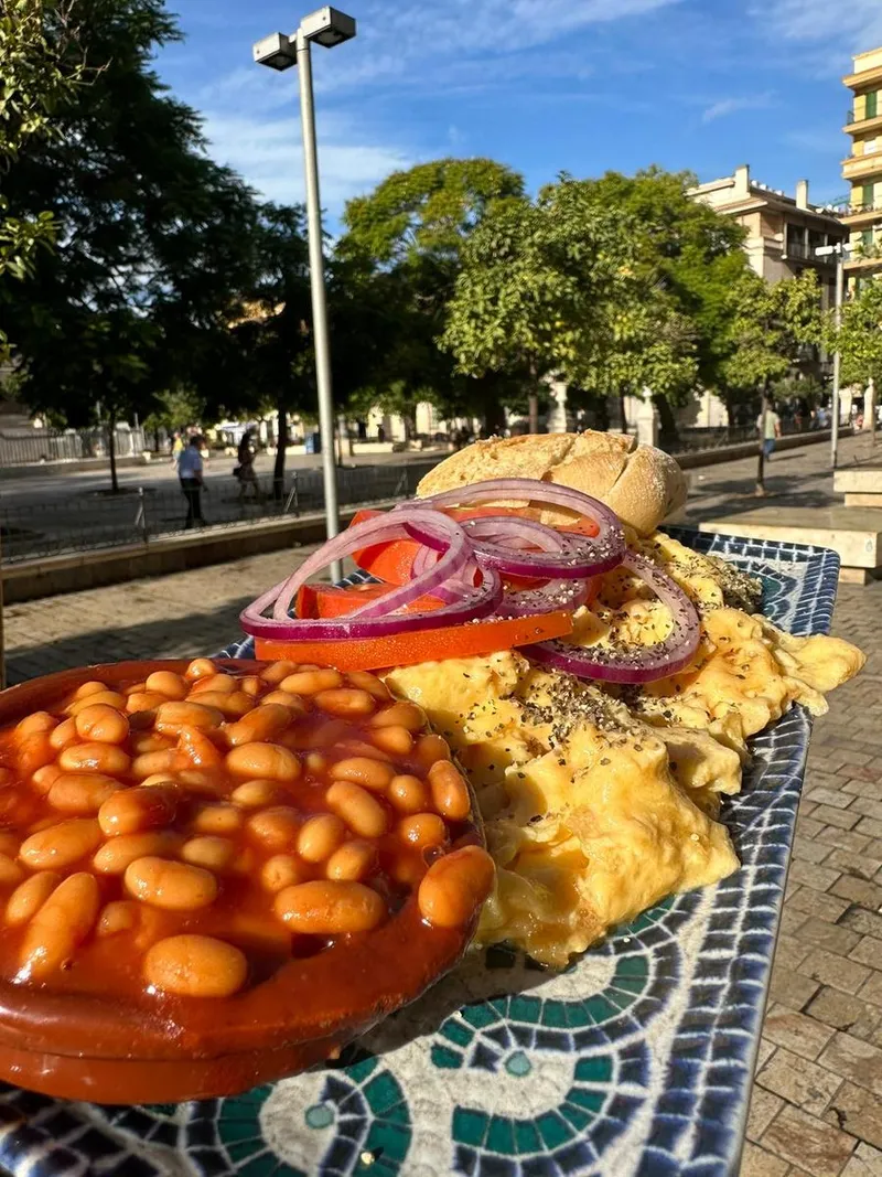 An English breakfast with baked beans and scrambled eggs on a terrace table on Plaza de la Merced